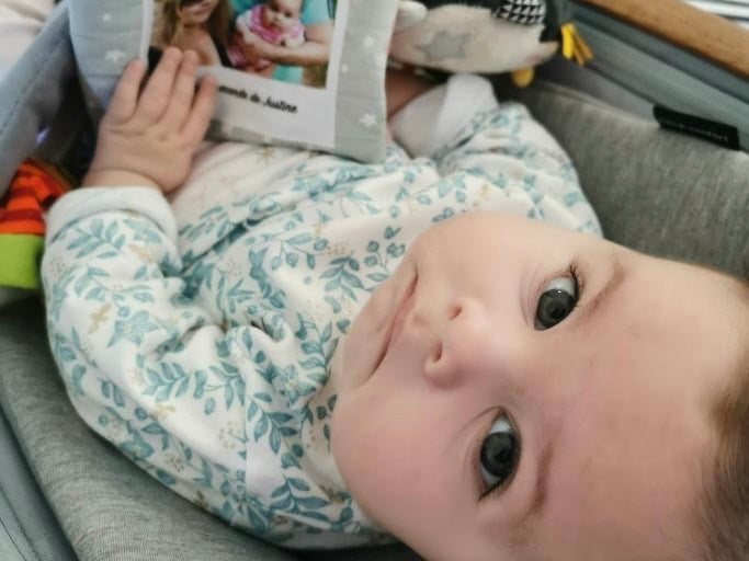 Bébé paisible avec son livre doudou pendant les vacances en famille