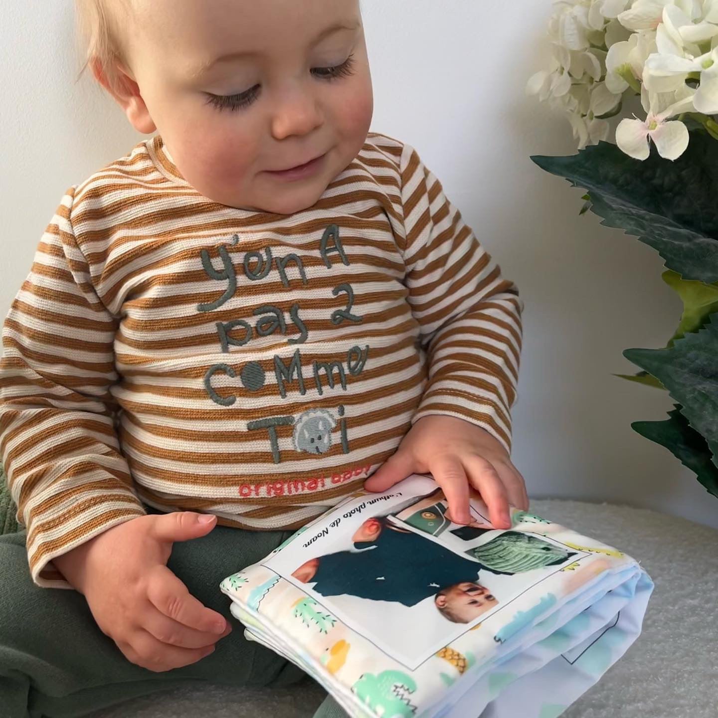 bébé en train de regarder les photos de sa famille sur un livre en tissu personnalisé